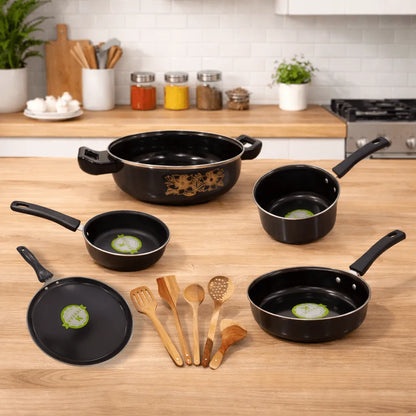 Set of black cookware on a wooden kitchen counter with wooden utensils.