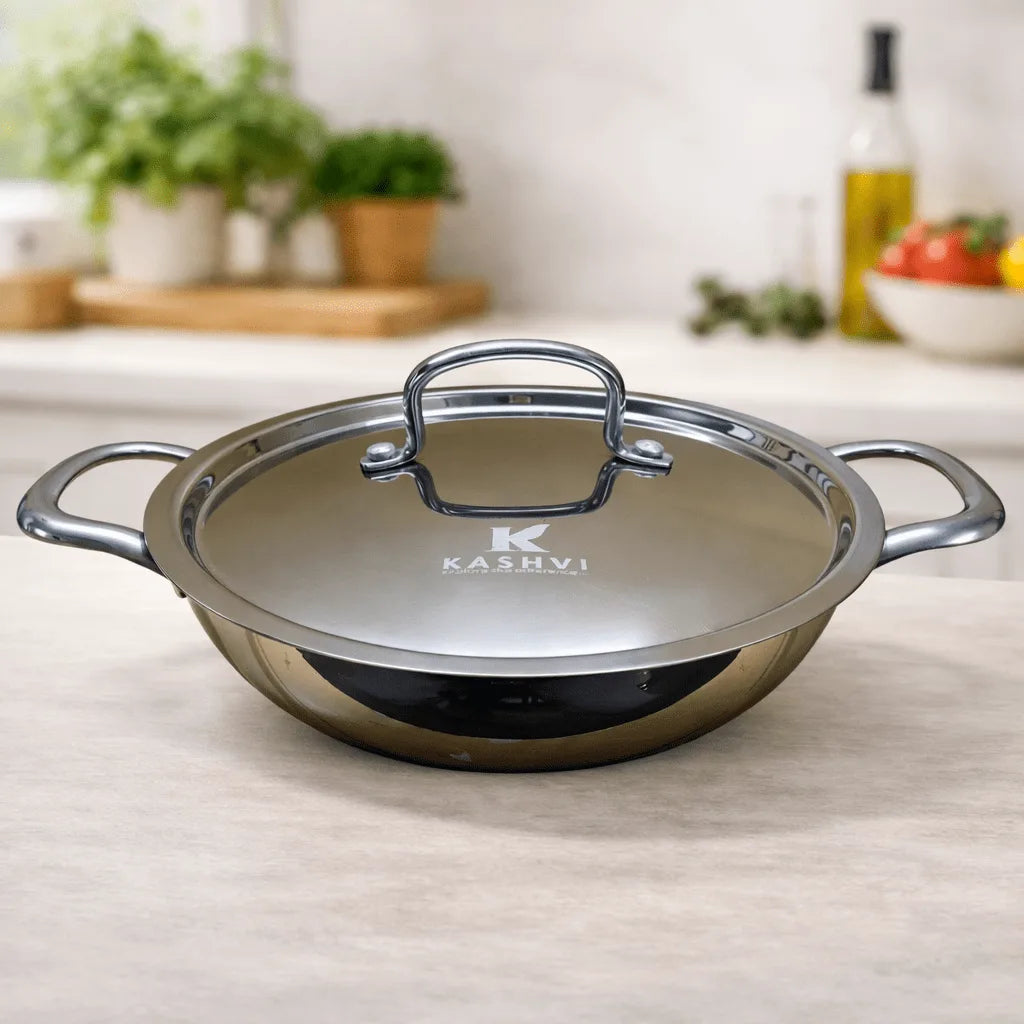 Stainless steel wok with lid on a kitchen counter, featuring the Kashvi brand.