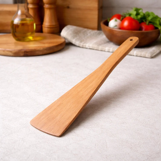 Wooden spatula on a kitchen counter with a bowl of vegetables in the background