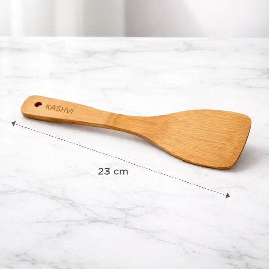 Wooden spatula with 'KASHVI' branding on a marble surface