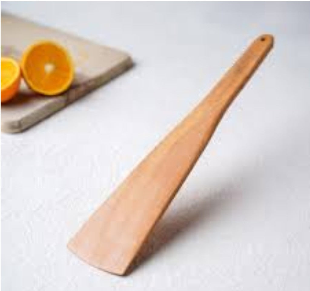 Wooden spatula on a white surface with oranges in the background