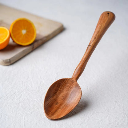 Wooden spoon on a light surface with oranges in the background